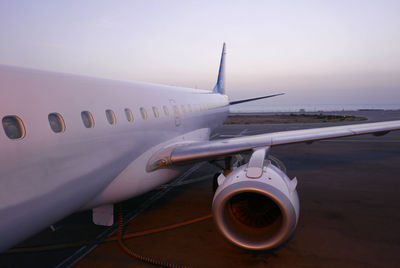 Airplane on airport runway against sky during sunset