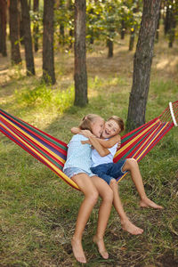 Happy boy embracing sister sitting on hammock