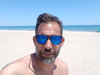 Portrait of man in sunglasses at beach during sunny day