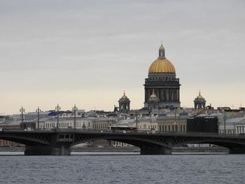 Bridge over river in city against sky