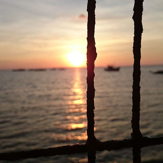 sunset, water, sea, tranquil scene, tranquility, beauty in nature, sky, scenics, nature, silhouette, horizon over water, sun, orange color, idyllic, reflection, cloud - sky, tree trunk, focus on foreground, outdoors, rippled