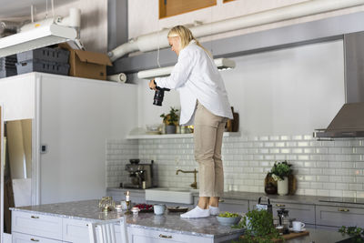 Woman photographing in kitchen