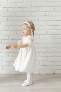 Portrait of cute girl standing against brick wall