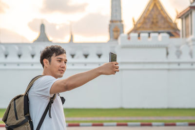 Young man with arms raised standing in city