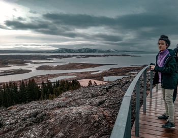 Woman standing by lake against sky