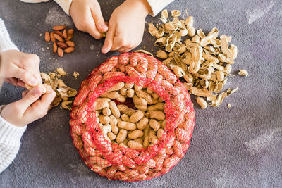 Peanut husks and a mesh bag with brown nuts on the table. baby hands peeling nuts in the background