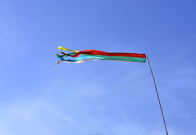 Low angle view of flag against blue sky