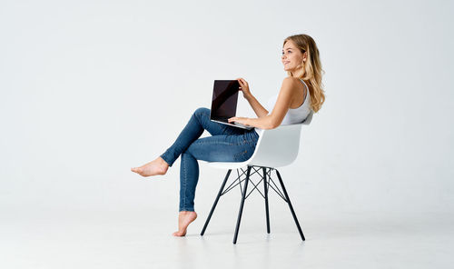 Woman sitting on chair against white background