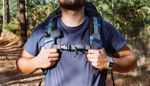 Midsection of man holding camera in forest