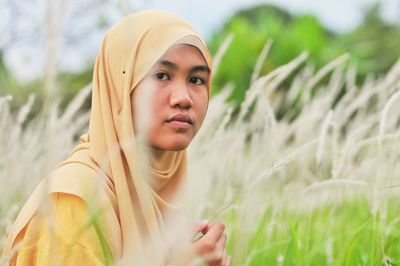 Portrait of beautiful young woman lying on field