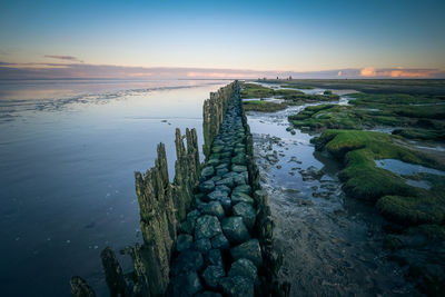 Stack of rocks on beach against sky during sunset