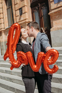 Valentines day celebration and dating concept. happy loving couple with red love balloons in the 