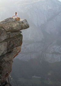 Man sitting on rock against mountain