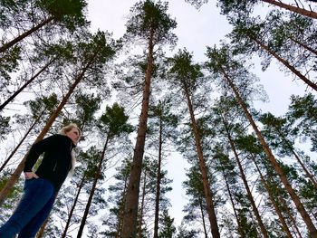 Low angle view of man standing by tree in forest
