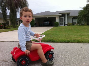 Boy sitting on toy car at yard