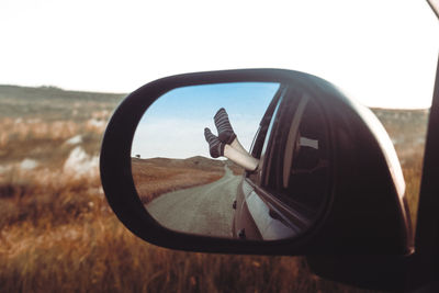 Reflection of man on side-view mirror