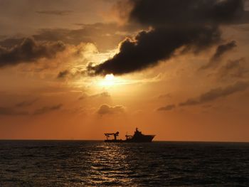 Silhouette boat in sea against sky during sunset