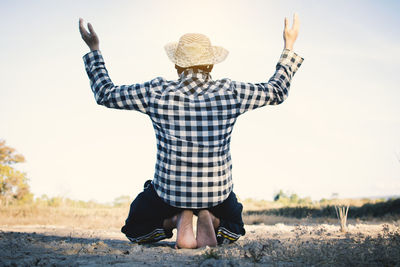 Rear view of man standing on field against sky