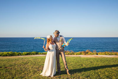 Woman with arms raised against sea against clear sky