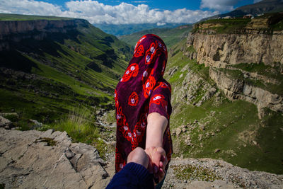 Midsection of woman on rock against mountains