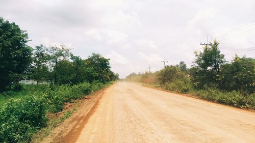 Road amidst field against sky