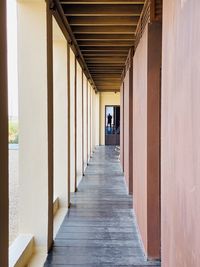 Rear view of man walking on footpath amidst building