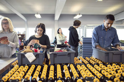 Volunteers checking for objects in crate on production line at workshop