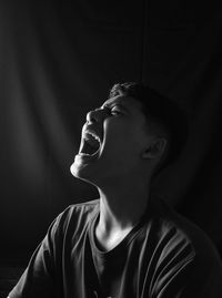 Young man looking away against black background