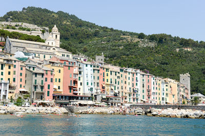 Buildings by sea against clear sky