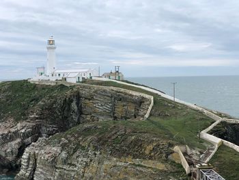 Lighthouse by sea against sky