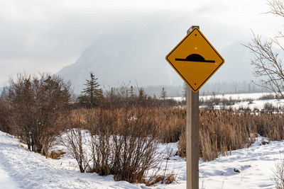 Information sign on snow covered field against sky