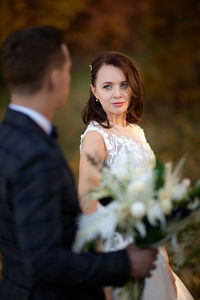 Portrait of smiling couple standing against trees