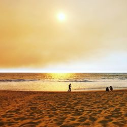 Silhouette people on beach against sky during sunset