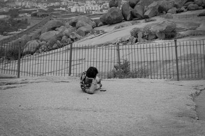 Rear view of boy sitting on railing