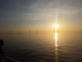 Silhouette of man on sea against sky during sunset