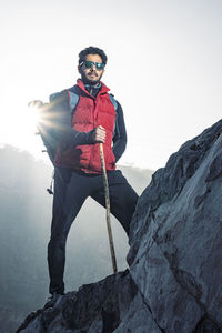 Man standing on rock against sky