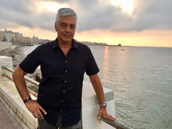 Portrait of smiling man standing in sea against sky