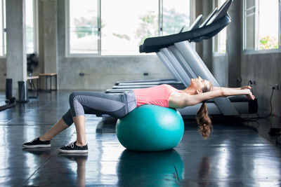 Side view of woman exercising with fitness ball in gym