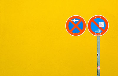 Close-up of road sign on yellow wall