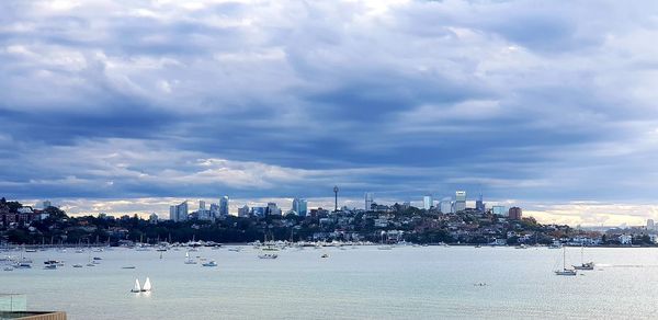 Panoramic view of buildings by sea against cloudy sky