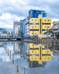 Information sign on river by buildings in city against sky