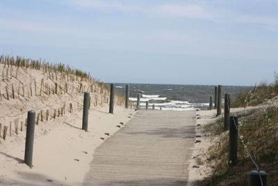 Wooden posts on beach against sky