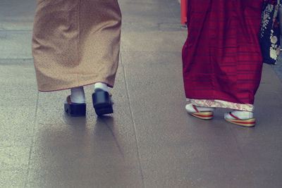 Low section of women walking on sidewalk