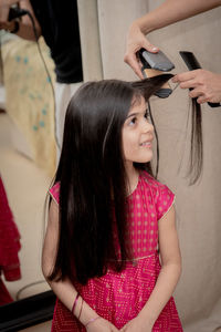 Hairdresser straightening the hair of girl 