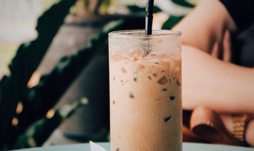 Close-up of hand holding drink on table