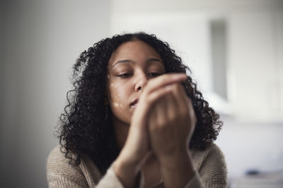 Pensive young woman picking at nails