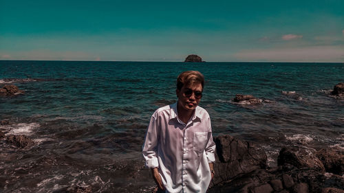 Young man standing in sea against sky