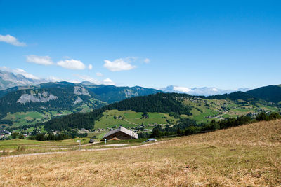 Scenic view of field and mountains against blue sky