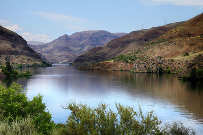 Scenic view of lake by mountains against sky