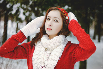 Portrait of young woman in snow forest in scarf and gloves.